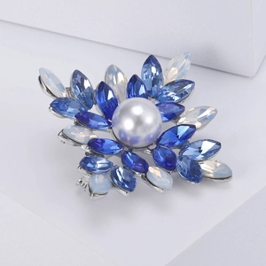 Detail of flower cluster brooch with round white pearl and blue marquise crystals