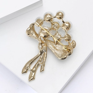 Détail du revers d'une broche fleur dorée montrant le fermoir de sécurité et les perles