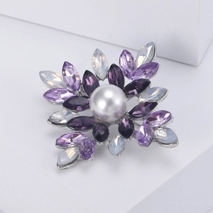 Detail of vintage flower brooch with purple rhinestones and central white pearl