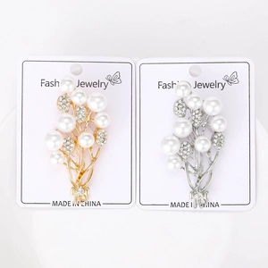 Detailed view of gold and silver floral brooches with white pearls and sparkling zircons