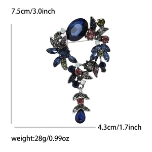 Détail macro de la broche fleur vintage en alliage avec strass et pendentif goutte bleue