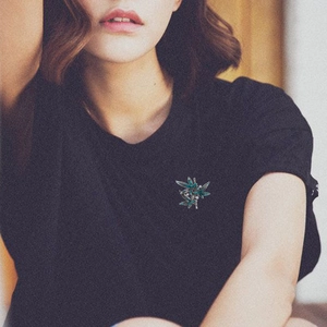 Bamboo leaf brooch with green enamel and white pearls pinned on a black T-shirt