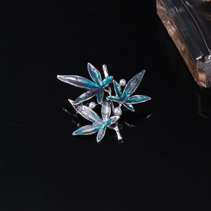 Detail view of a vintage maple leaf brooch with blue enamel and three white pearls