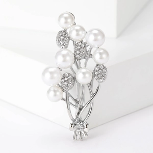 Detailed macro of a silver floral bouquet brooch with pearls, rhinestones, and bow