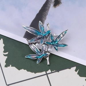 Close-up of maple leaf brooch with blue-green enamel petals and three small white pearls