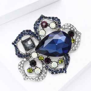 Detalle del broche de flor con gran cristal azul y pedrería multicolor en base plata