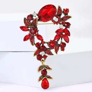 Gros plan d'une broche de style vintage avec cristaux rouges et d'élégants détails dorés