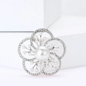 Elegant silver flower brooch with large pearl and sparkling rhinestones on white blocks