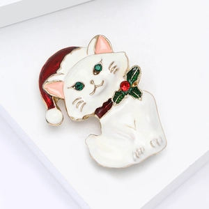 Detailed close-up of a Christmas cat brooch with red hat and green rhinestone eyes