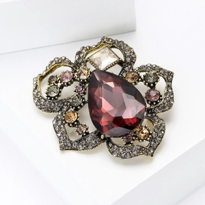 Primer plano de broche de amapola vintage con cristal rojo pera y detalles en metal oro