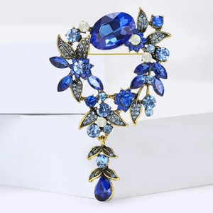 Vue macro d'une broche dorée vintage avec cristaux bleus et détails floraux en feuilles