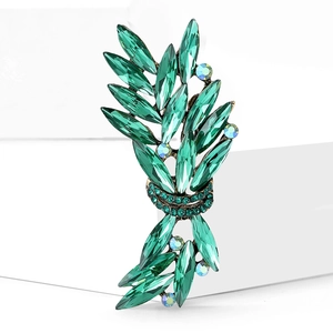 Macro shot of leaf-shaped brooch with emerald marquise crystals and green rhinestones
