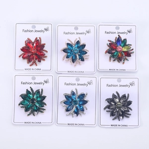 Detail view of six colorful crystal flower brooches in varied shades with fashion jewelry tags