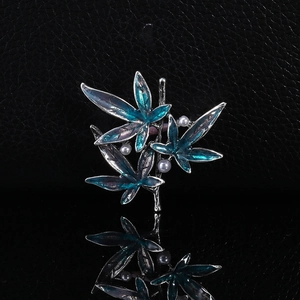 Bamboo leaf brooch with blue enamel and white pearls on elegant black reflective surface