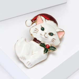 Close-up of enamel cat brooch with Christmas hat, red rhinestone and green gemstone eyes