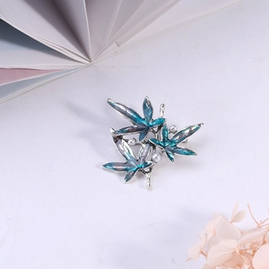 Detailed macro of a gradient blue enamel maple leaf brooch with small white pearls