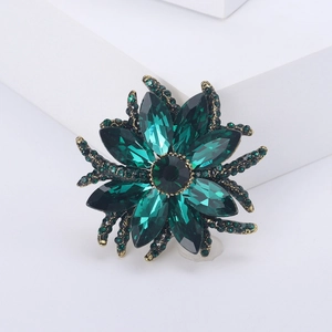 Close-up of green crystal floral brooch with vintage gold finish on white steps