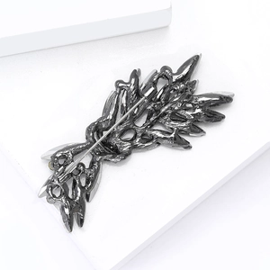 Detailed macro view showing the safety pin closure and gunmetal texture of the brooch