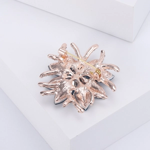 Detail of rose gold flower brooch back showing safety rotary clasp and metal texture