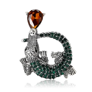 Spilla vintage a forma di coccodrillo con cristalli verdi e gemma ambrata su bianco