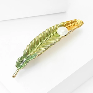 Vintage gold and green feather brooch with large white pearl on white geometric background