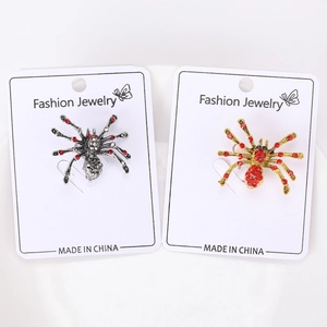 Detail of silver and gold spider brooches with red crystals on a white card display