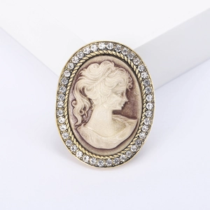 Vintage oval cameo brooch with crystal accents and golden frame on a white background