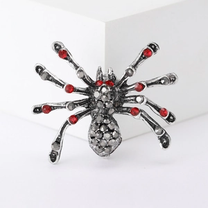 Close-up of vintage spider brooch with red and grey rhinestones on a white pedestal