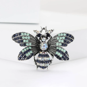 Detailed macro view of an antique silver bee brooch with sparkling blue and AB crystals