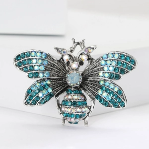 Exquisite silver-tone bee brooch with sparkling blue rhinestones and crystals on white stand