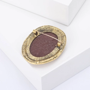 Detail view of the vintage oval brooch back with secure pin and textured gold alloy finish