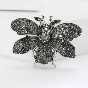 Macro detail of silver tone bee brooch with dark grey sparkling crystals on wings