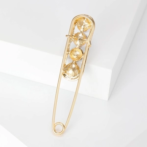 Schicke goldene Sicherheitsnadel-Brosche mit Dekorelementen auf weißem Hintergrund