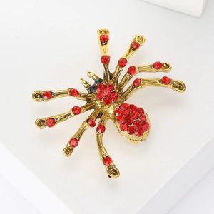 Macro detail of a vintage gold spider brooch featuring vibrant red rhinestone embellishments