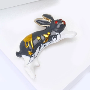 Détail d'une broche lapin en émail avec étoiles dorées sur des marches blanches