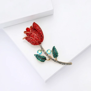 Élégante broche tulipe en or avec strass rouges, verts et bleus sur un socle blanc
