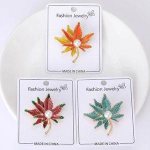 Detail of maple leaf brooches with drip oil enamel texture and a center white pearl