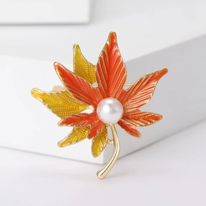 Elegant maple leaf brooch with orange enamel and pearl on white geometric stone base