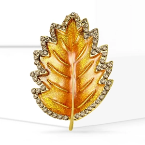 Elegant gold leaf brooch with sparkling crystals and glitter finish on white background