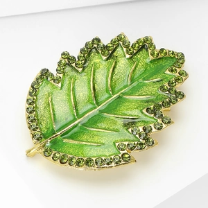 Detailed view of leaf brooch with green enamel and sparkling rhinestones on gold base