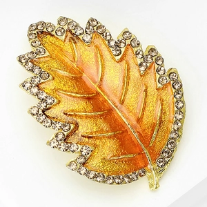 Detailed close-up of maple leaf brooch with orange enamel and crystal rhinestones