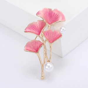 Élégante broche feuille de ginkgo avec dégradé rose et perles sur un socle blanc