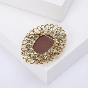 Close-up of vintage gold-tone oval brooch with hollow lace edge and safety pin back detail