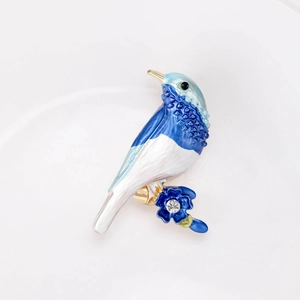 Dettaglio macro di spilla a forma di uccello in smalto blu con cristallo e oro
