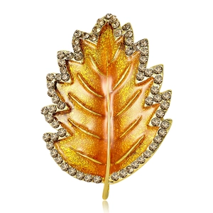 Leaf brooch with gold enamel and sparkling crystals on a clean white background