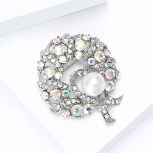 Detailed close-up of a wreath brooch with colorful rhinestones and a large white pearl