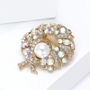 Macro shot of gold circular brooch with white pearl, rhinestones on white platform