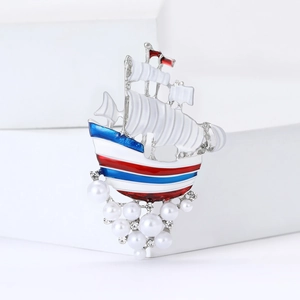 Elegant sailboat brooch with enamel colors, pearls, and rhinestones on white background