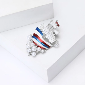 Enamel sailboat brooch with pearls and rhinestones on minimalist white display stand