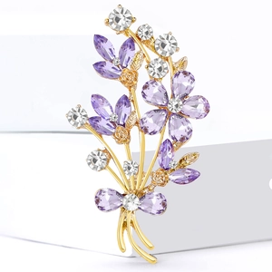 Elegant floral alloy brooch with purple crystals and gold bow on minimalist white cubes